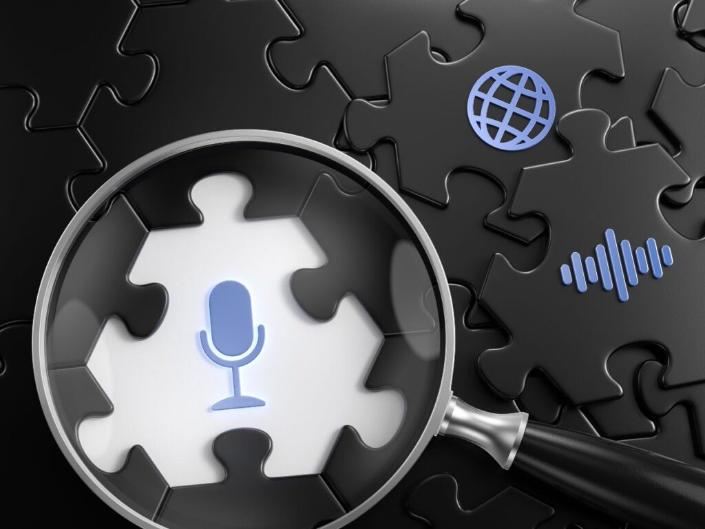 Magnifying glass over a puzzle piece with microphone and web icons.