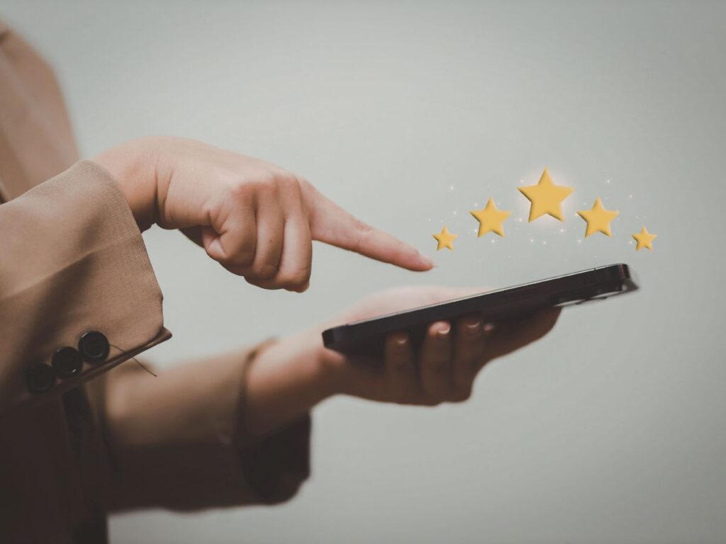 Hand using phone with glowing star ratings for feedback.