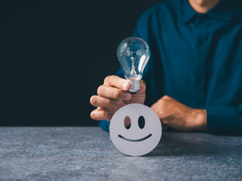 Person holding a lightbulb near a smile icon