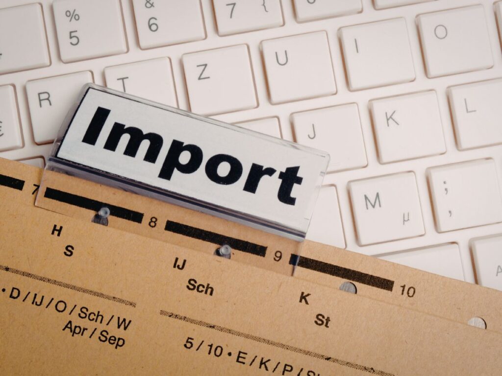 Import label tab on a file folder over a white keyboard.