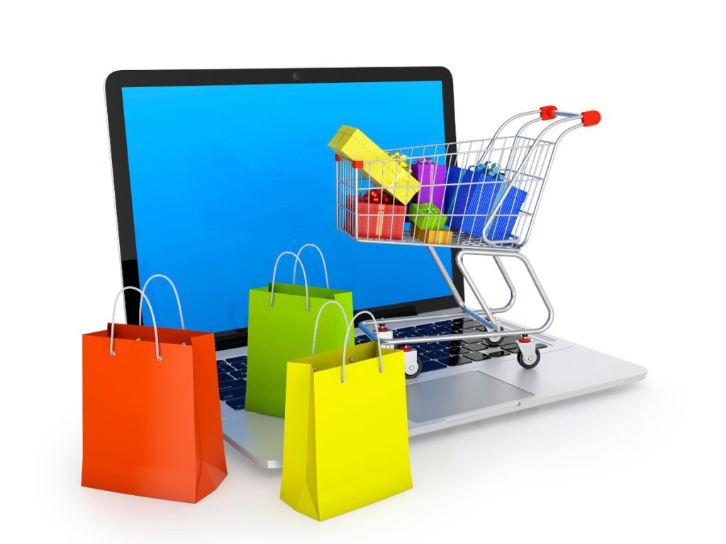 Shopping bags and cart emerging from a laptop.
