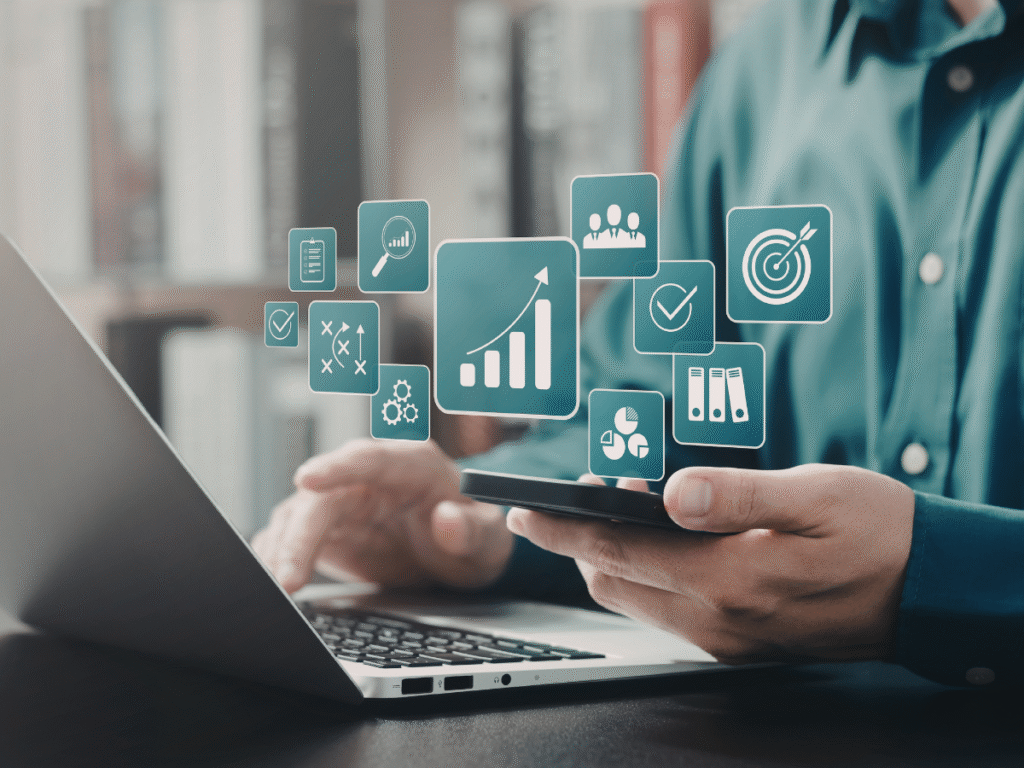 Person using phone and laptop with floating analytics icons.