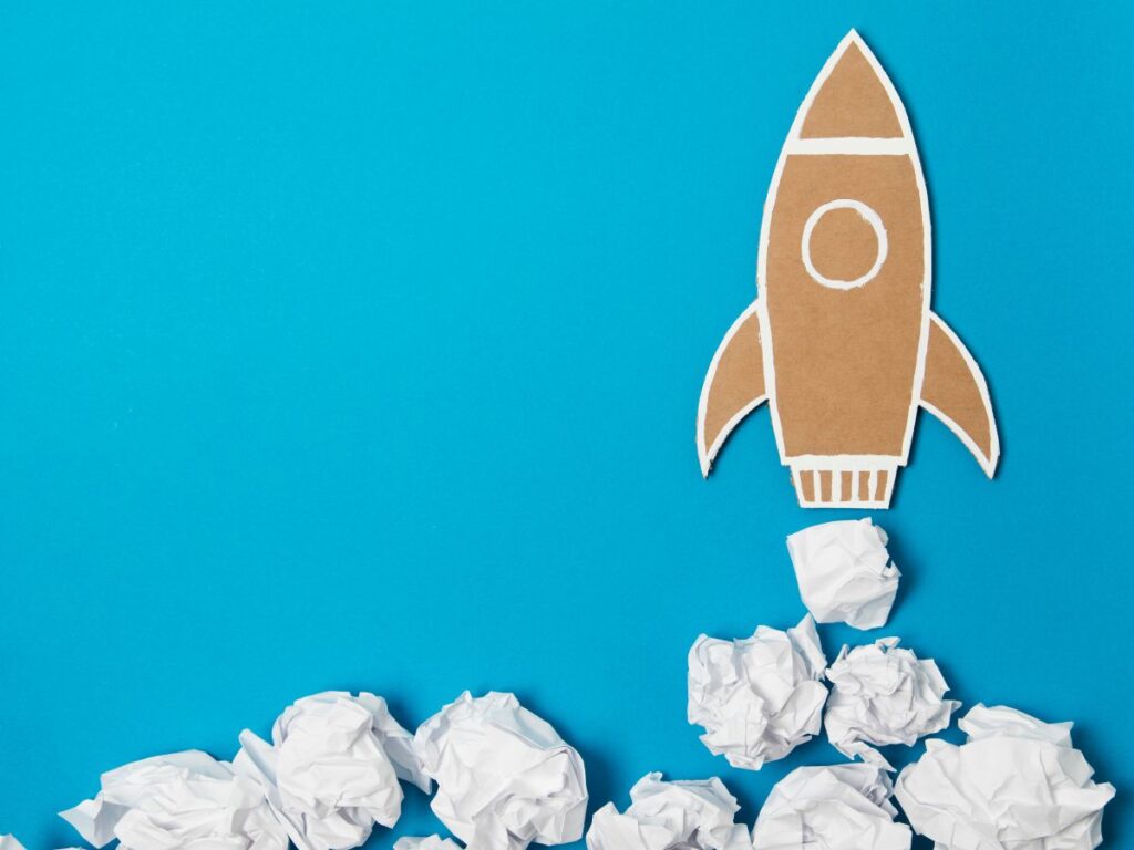 Paper rocket launching on a blue background.