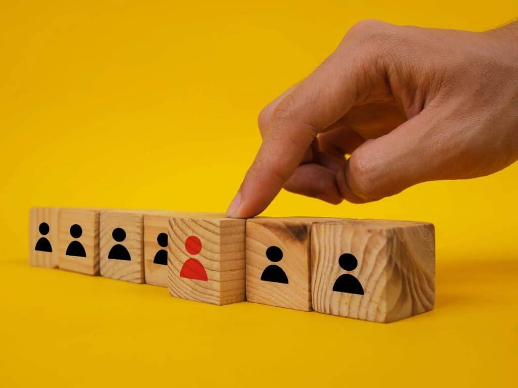 Hand selecting one figure among wooden blocks, showing choice.