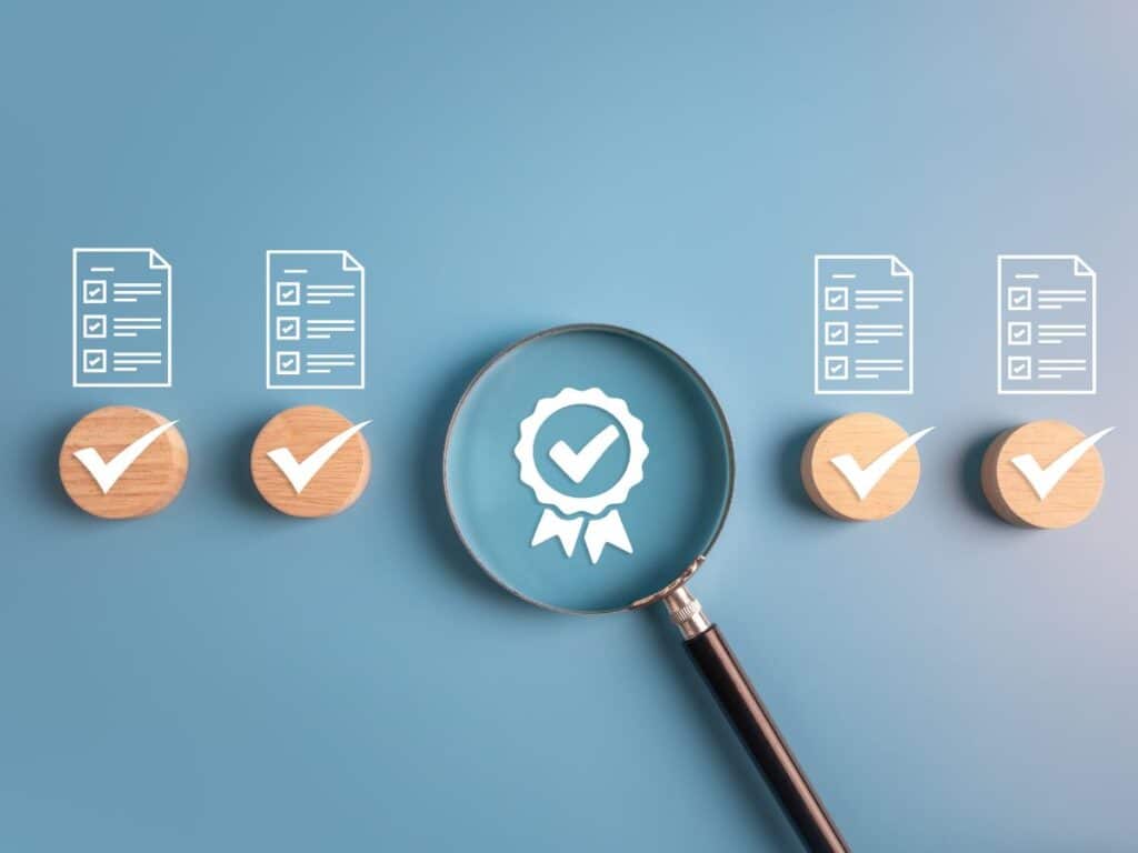 Magnifying glass over quality check icons on a blue background.