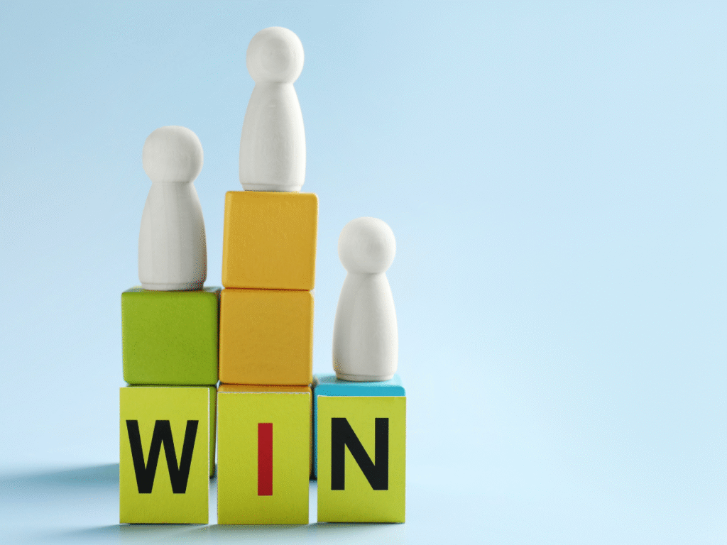 Wooden figures on blocks spelling “WIN” like a podium.