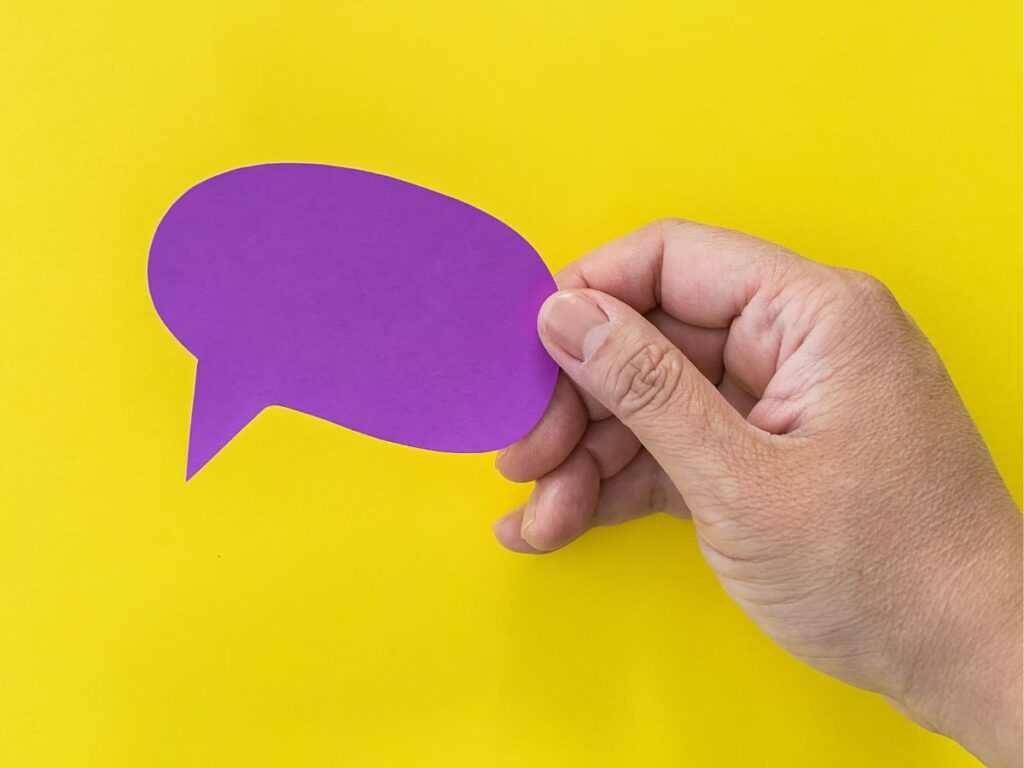 Hand holding a purple speech bubble cutout