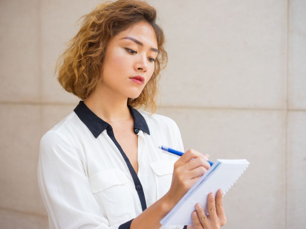 Woman writing notes in a notepad with a pen